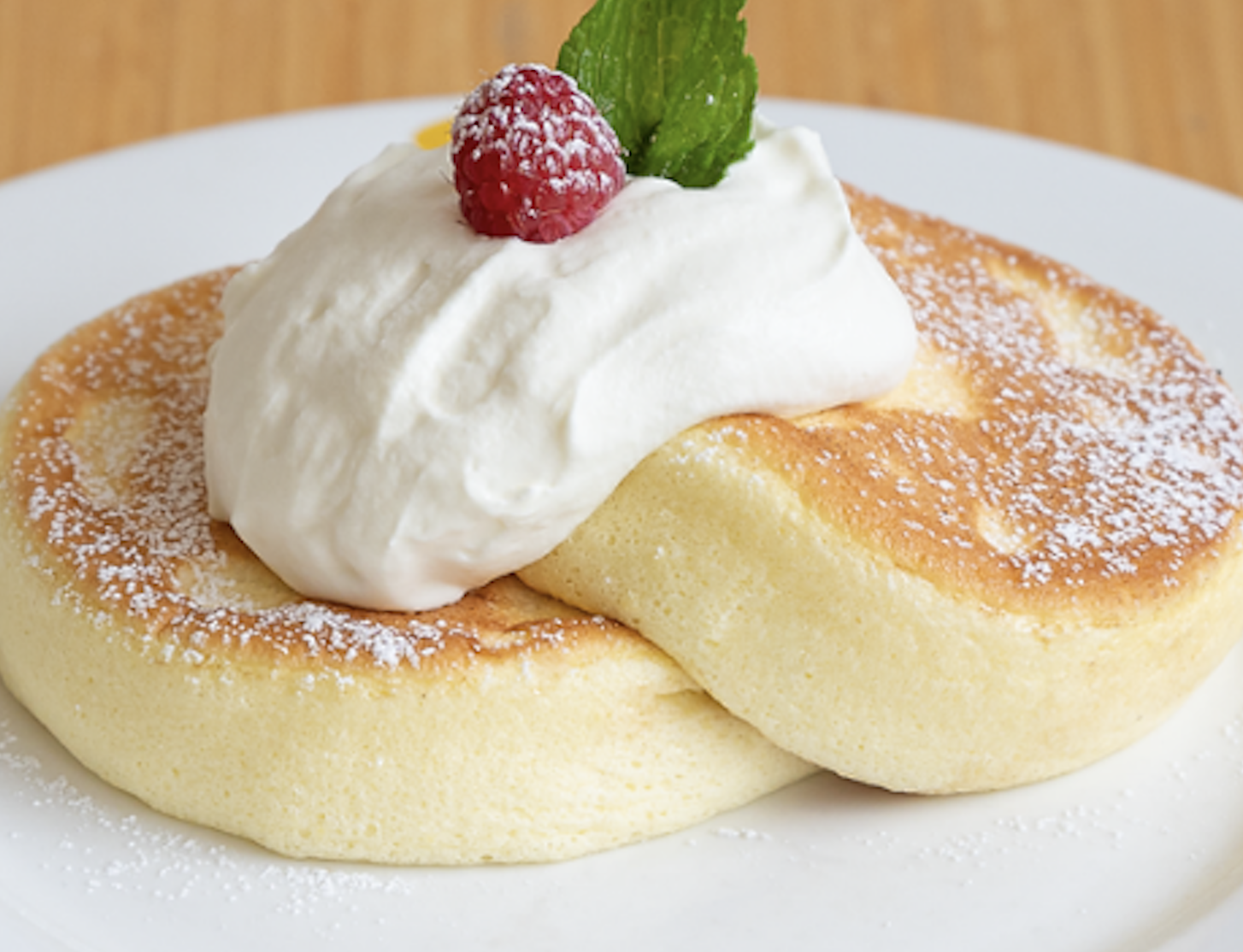 Pancake stack with cream and a strawberry on a white plate