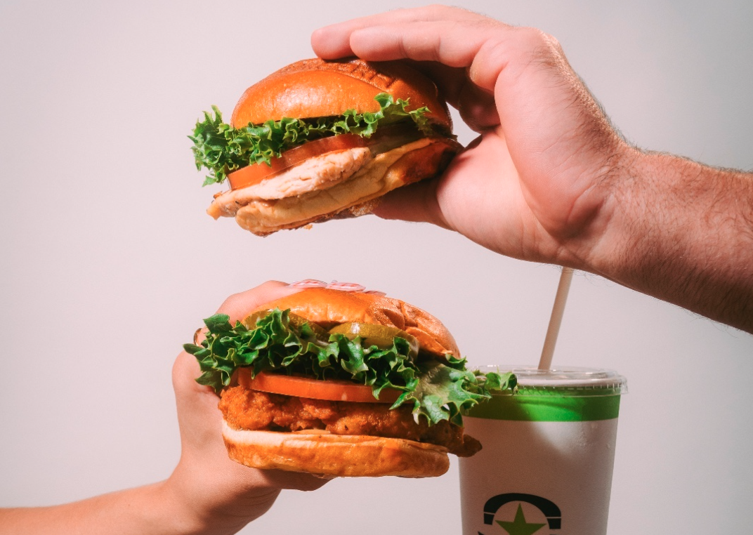 Two sandwiches being held in the air