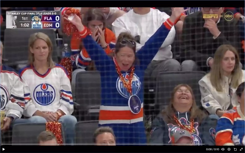 a woman in an Edmonton Oilers jersey appears to cheer a goal by the opposition Florida Panthers.