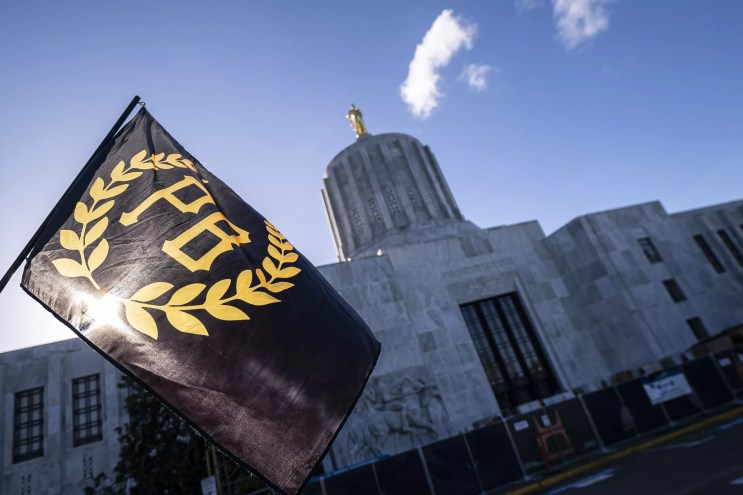 A flag for the extremist Proud Boys group flies against a blue, clear sky