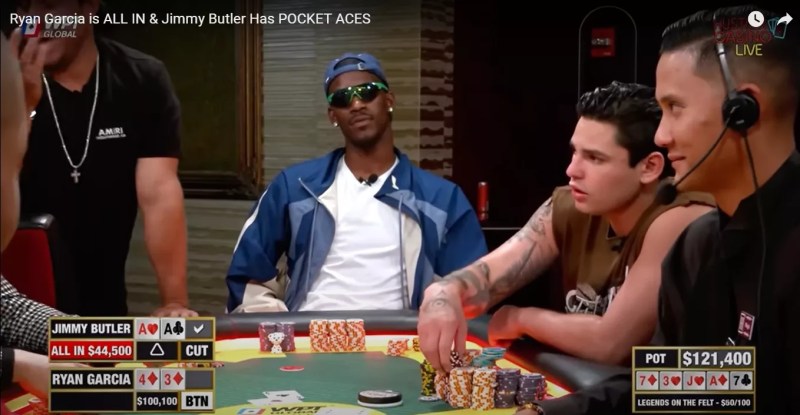 Jimmy Butler in sunglasses and backwards cap at a high stakes poker table