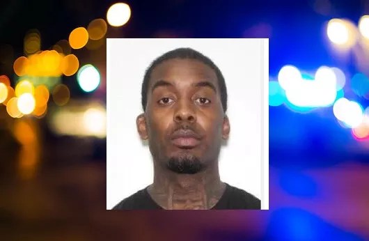 Booking photo of a man with neck tattoos staring blankly into camera