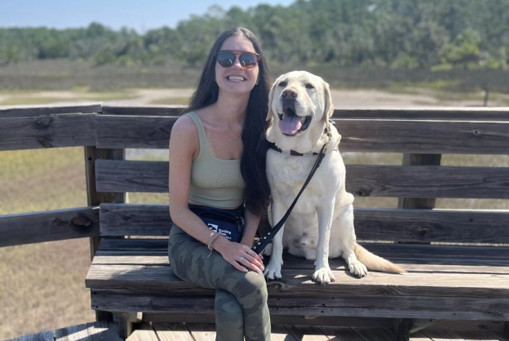 Marin Baumer and her seeing-eye dog Kegan sitting on a bench