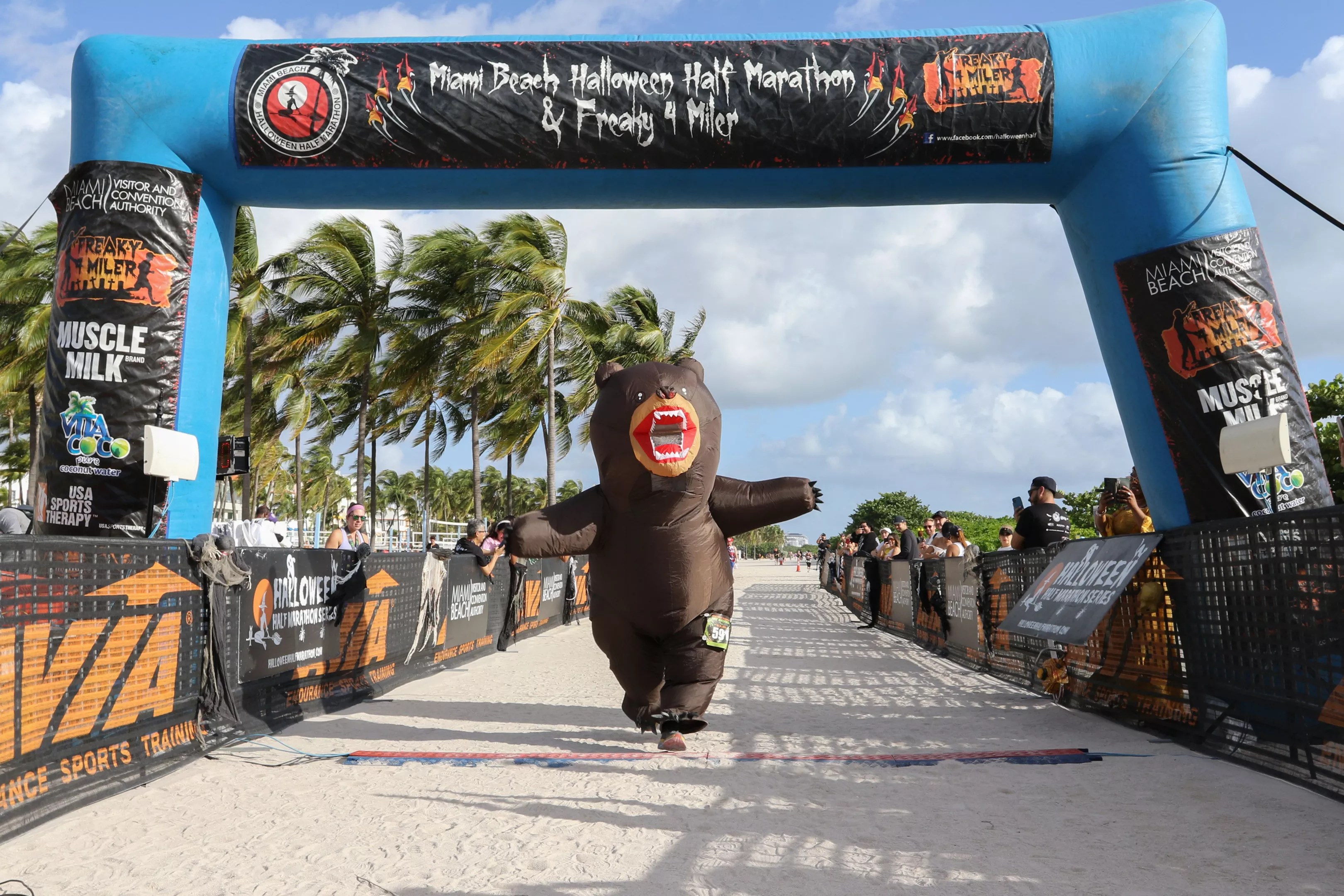 A person in a bear costume crossing the finish line