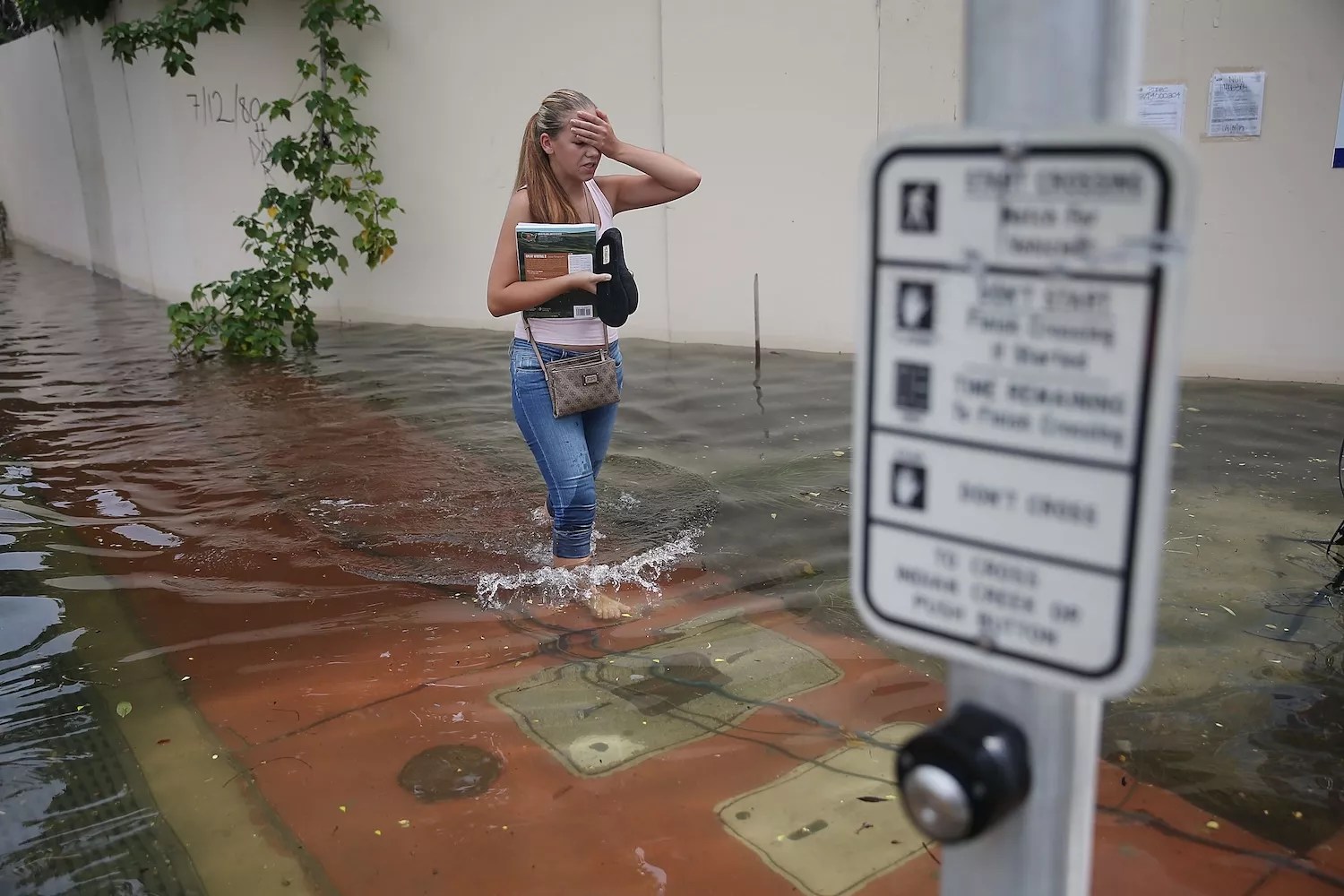 A woman walks through a street in Miami Beach that was flooded by the combination of the lunar orbit which caused seasonal high tides and what many believe is the rising sea levels due to climate change