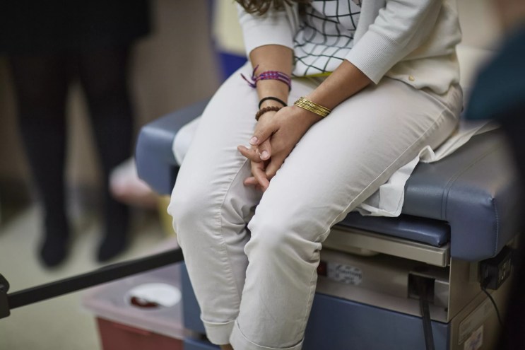 partial image of a clothed woman in an examining room