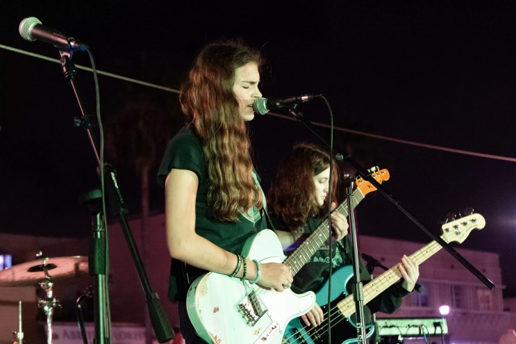 Lily Kaplan performing on stage with a guitar