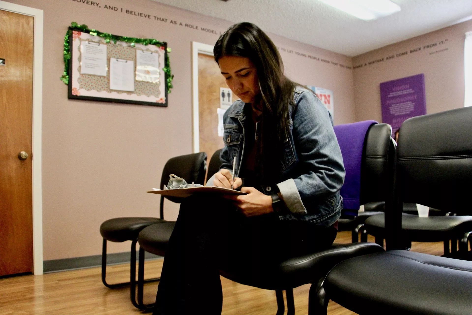 woman in the waiting room of a health clinic, filling out a form