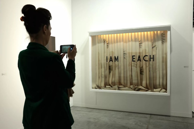 Woman snapping a photo of an artwork at Art Basel Miami Beach 2024