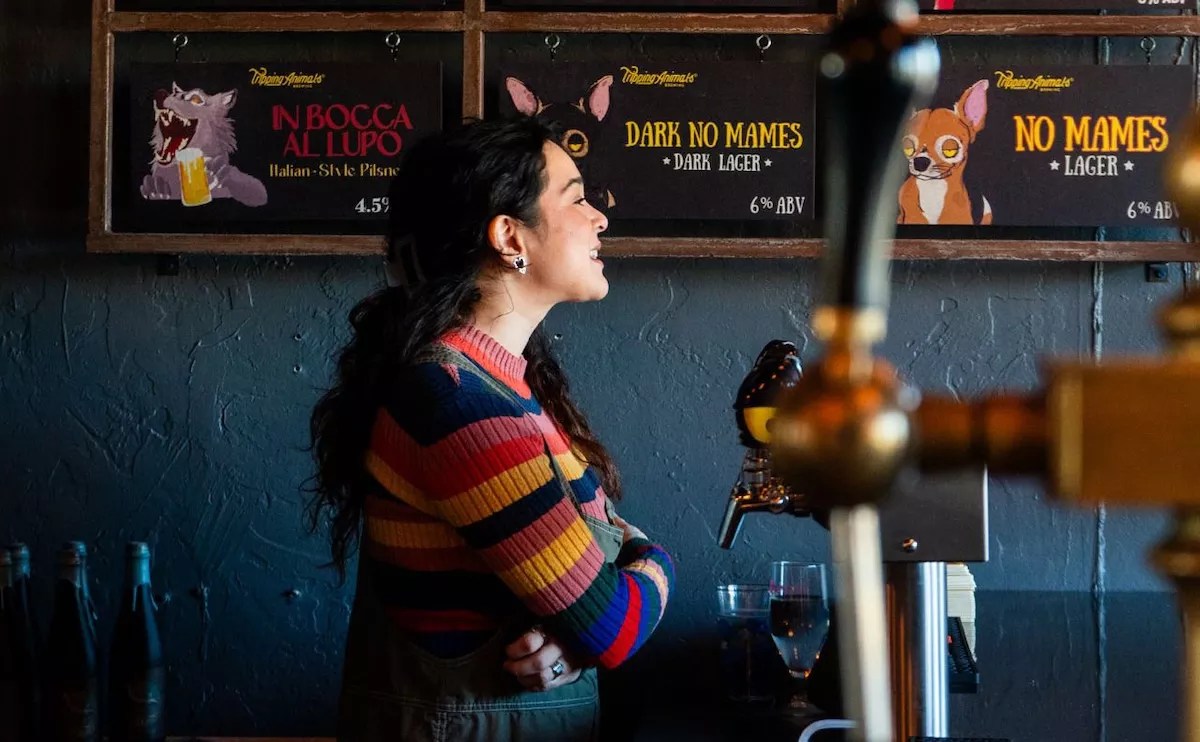 a woman in a striped sweater standing next to a beer tap