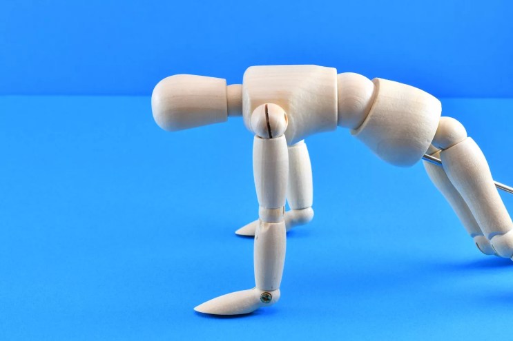 stock photo of an articulated wooden figure in a kneeling position as if vomiting
