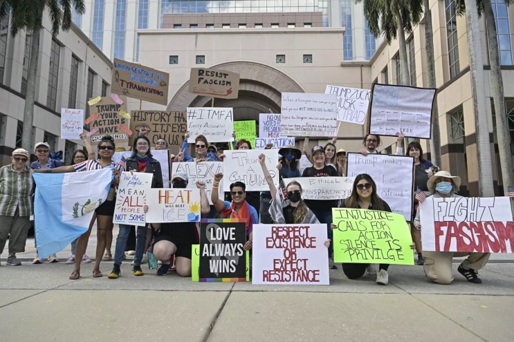 Protesters with signs pose outside the Palm Beach County courthouse
