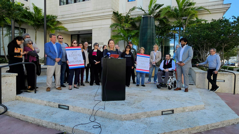 Laura Kelley, Chair of the Miami-Dade Democratic Party, speaks at a press conference while people stand behind her