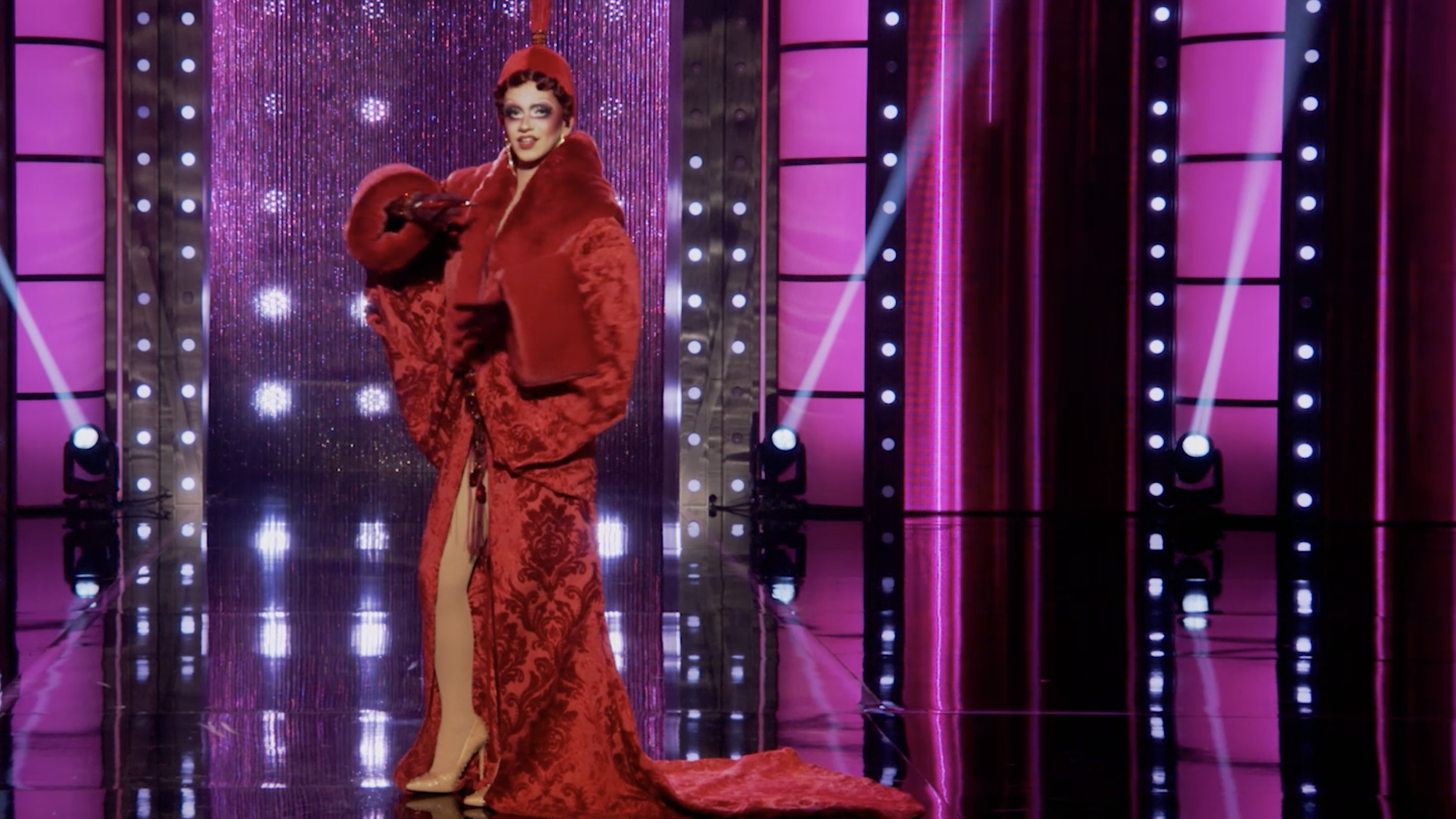 drag queen suzie toot wears a long red cocoon coat