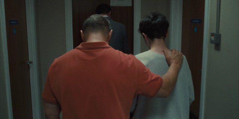 still from the Netflix show Adolescence. An adult man puts his arm around a young man