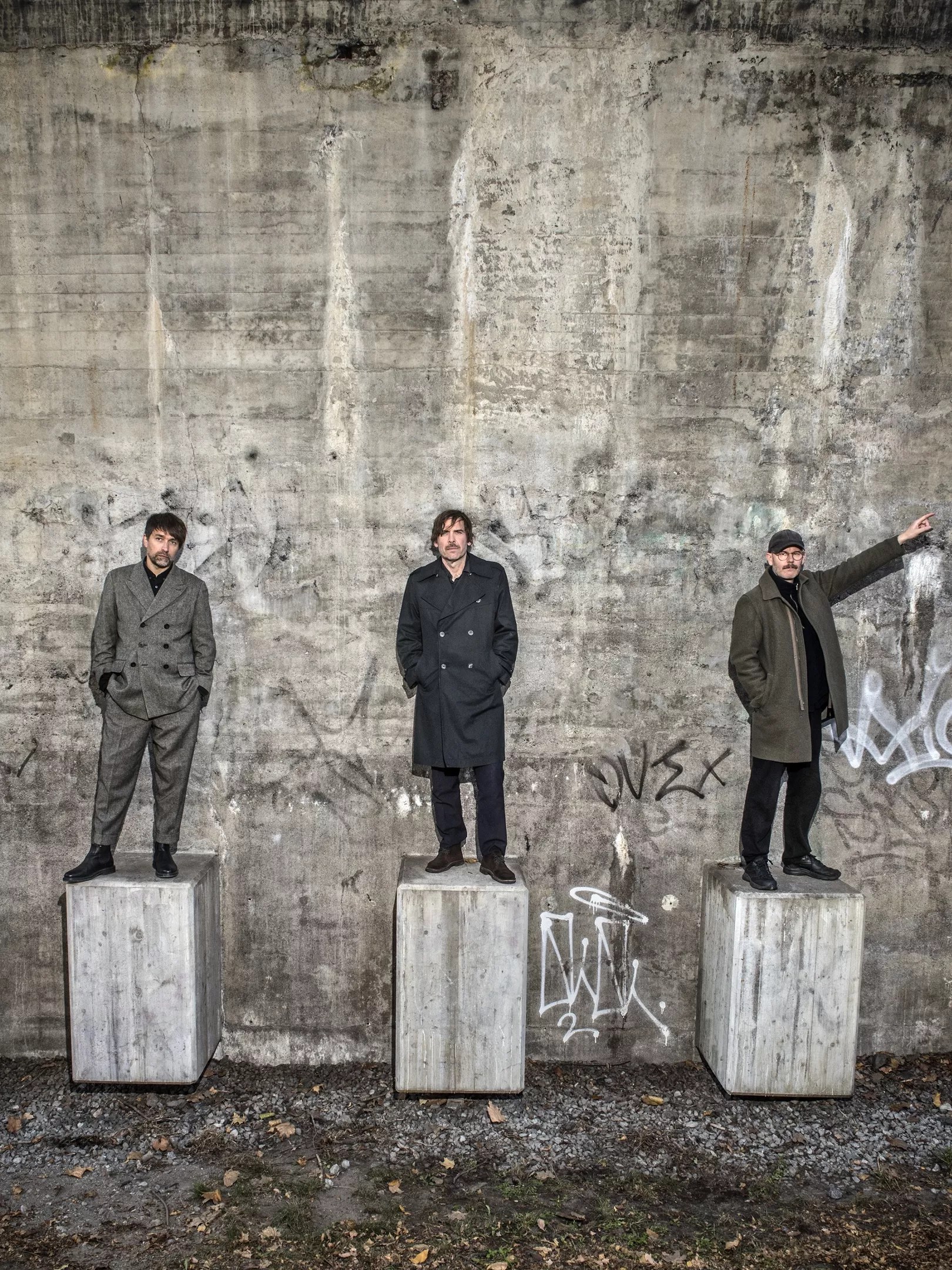 Three men stand on concrete blocks against a concrete backdrop. Very Swedish rock.