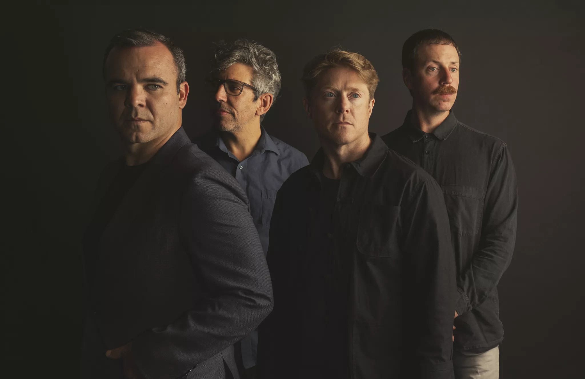 portrait of four band members standing side by side