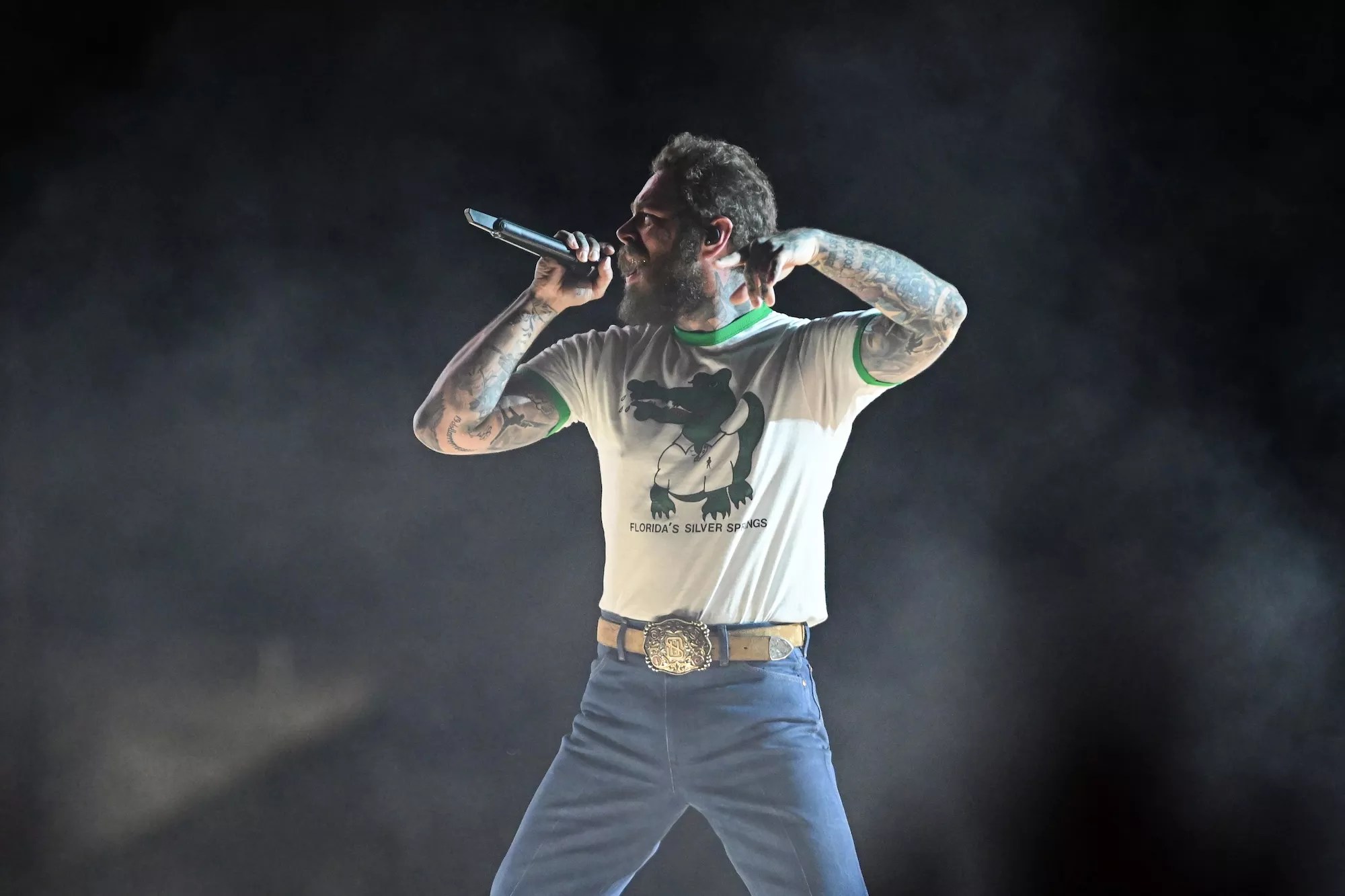 Post Malone performs in jeans and a Silver Springs Florida T-shirt featuing a cartoon alligator