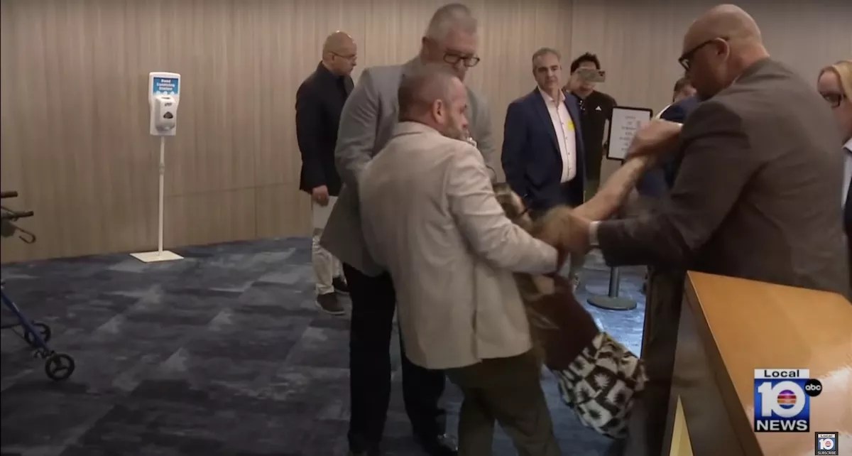 A photo of Miami-Dade Sheriff's Office deputies in khaki and gray suits forcibly removing a woman who was reportedly protesting an Immigration and Customs Enforcement (ICE) agreement with county jails.