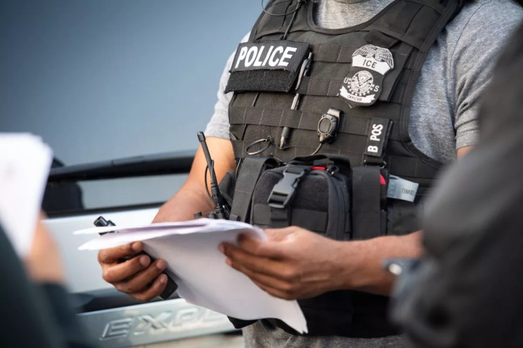 An ICE agent checks paperwork.