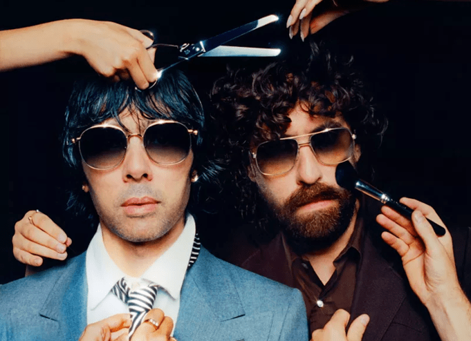 Two men are putting on makeup and getting a haircut