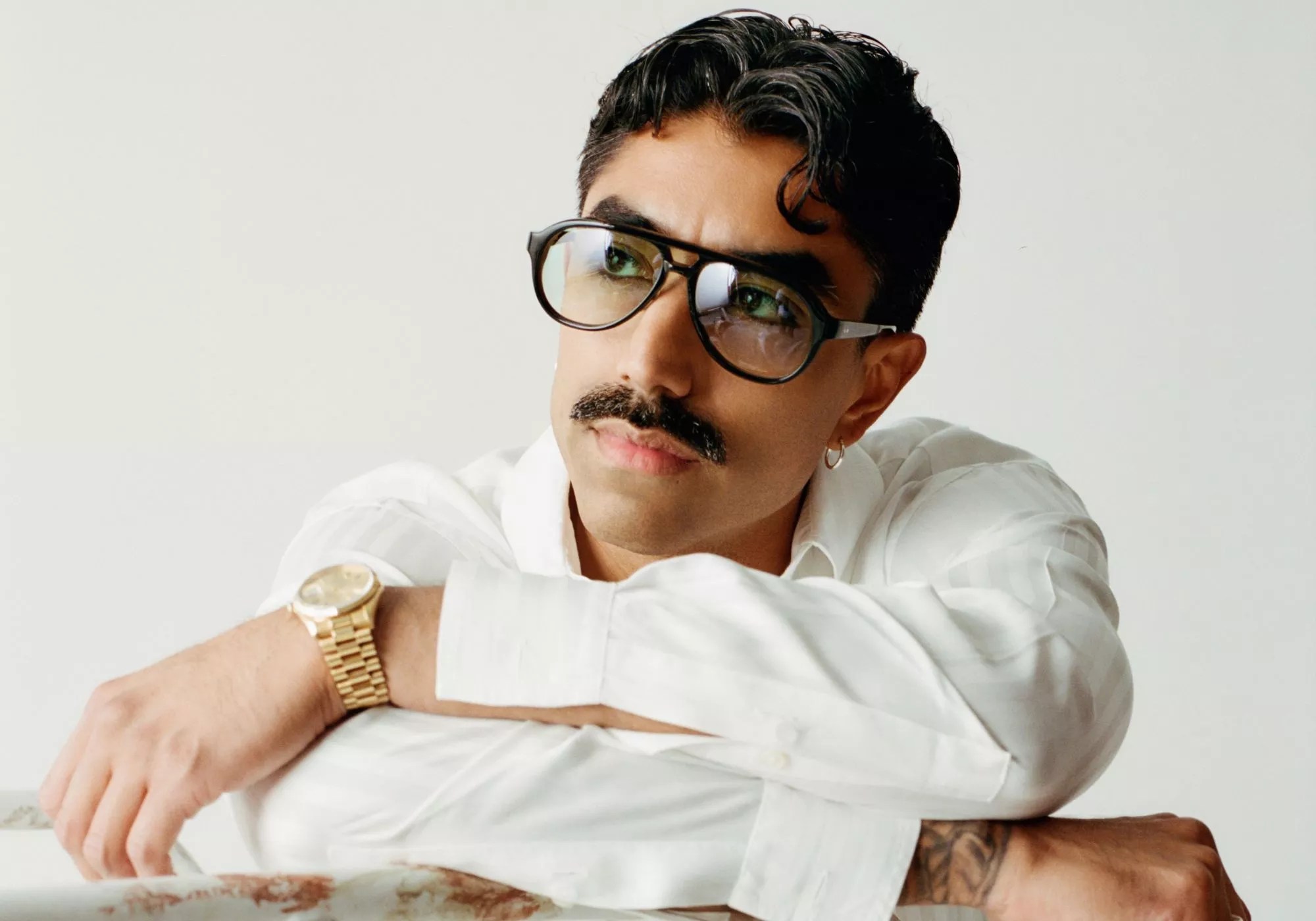 Portrait of a man wearing glasses and white clothing.