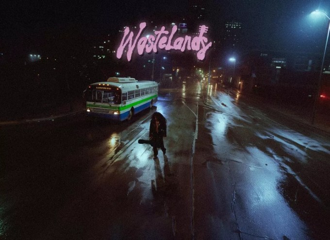 Image of a man walking at night carrying a guitar.