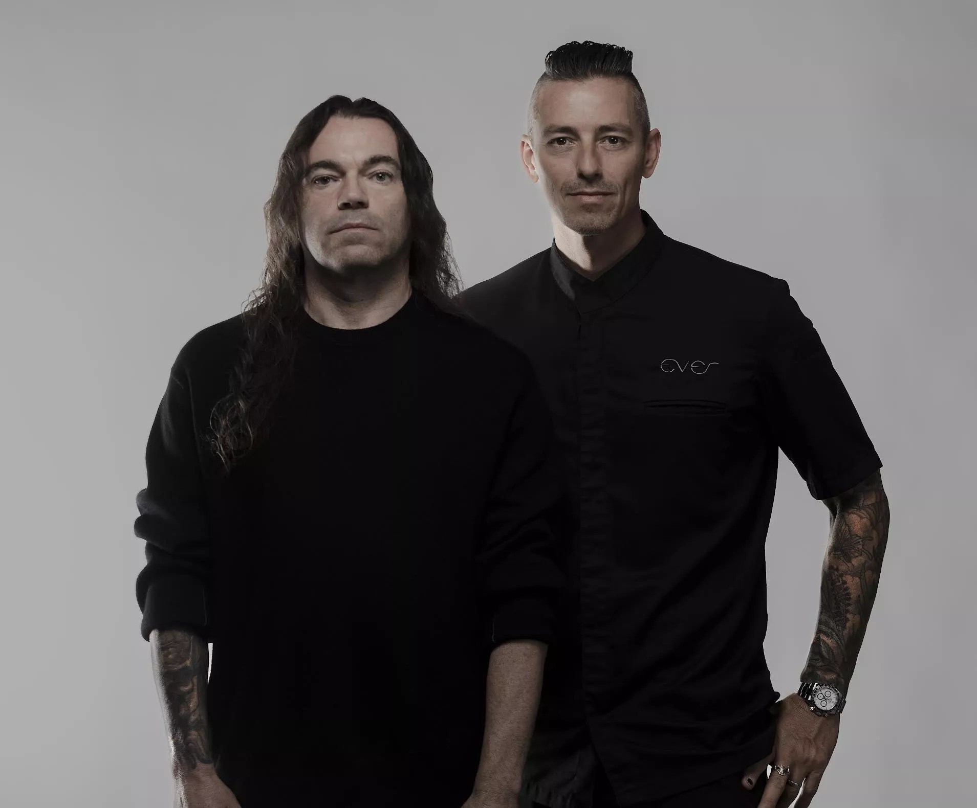 Two men posing for the camera wearing black.