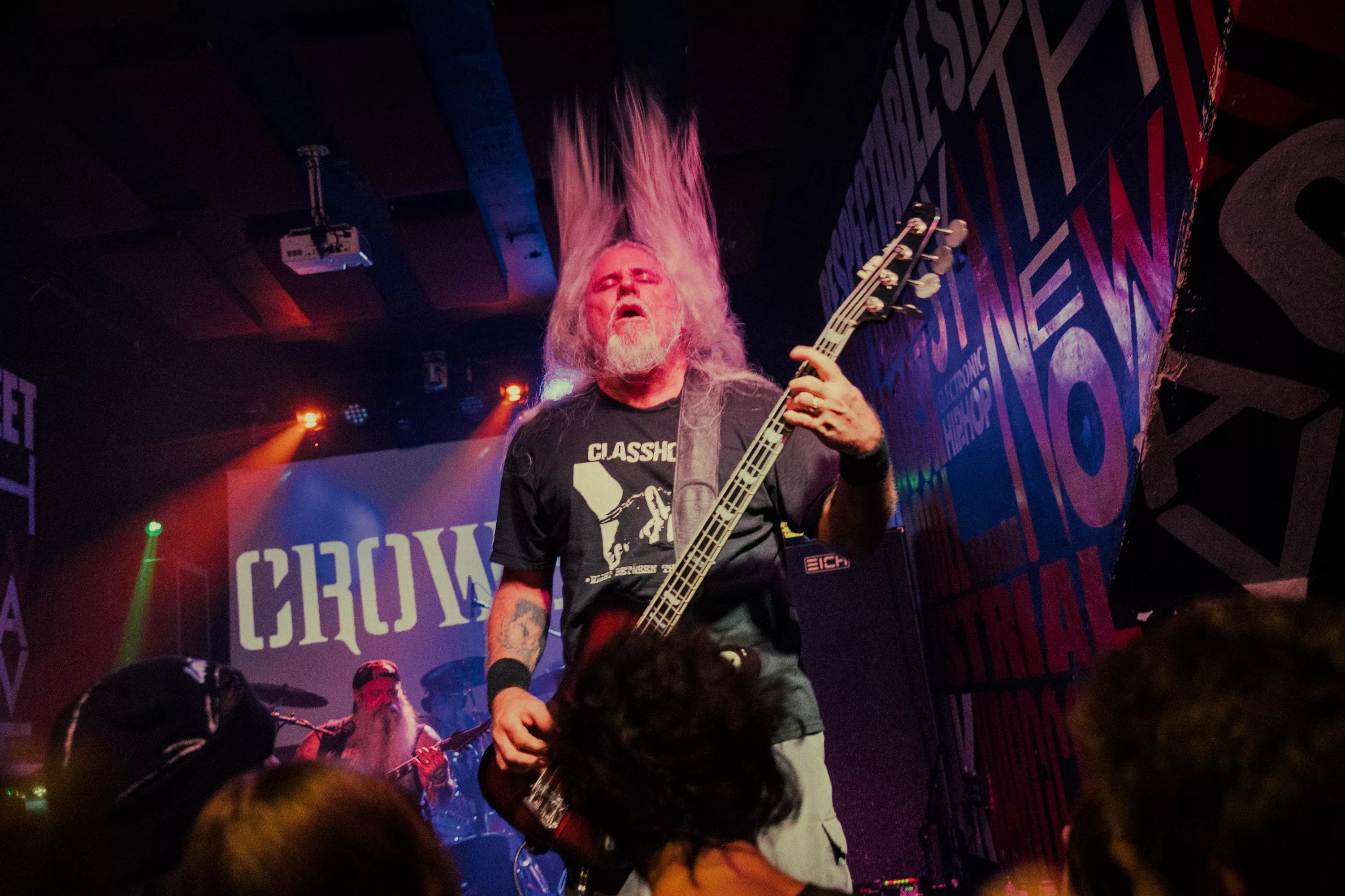 Bass player of a metal band performing in front of a crowd.