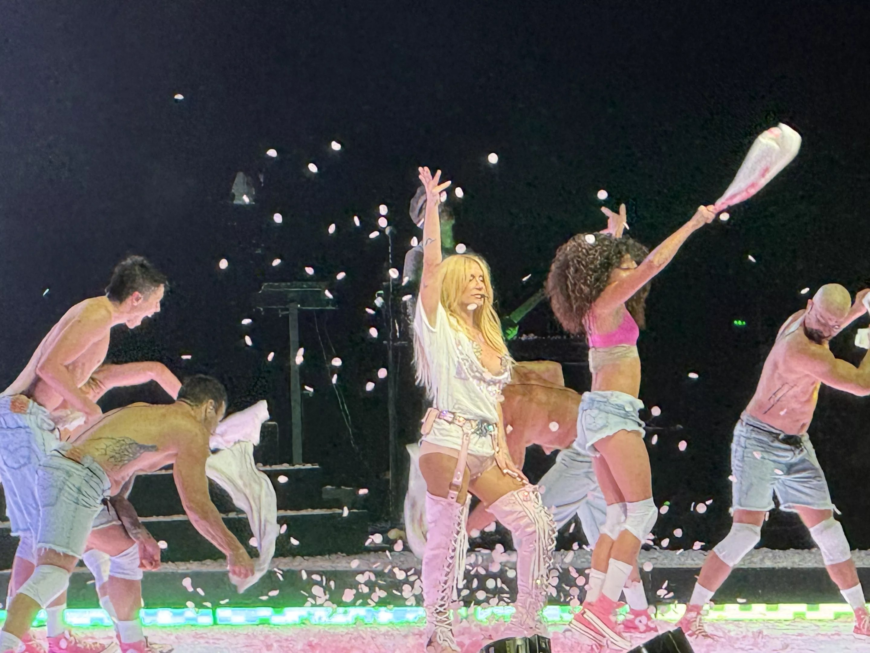 Woman on stage wearing white shorts and high boots.