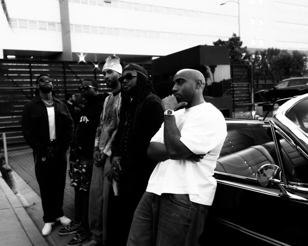 group of men sitting by a car.