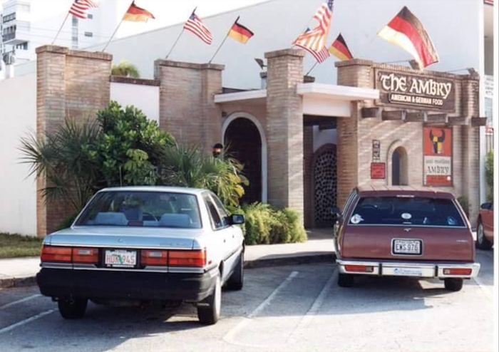 two cars from the '80s parked out of a restaurant