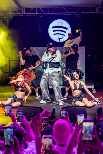 A man performing on stage with dancers and a Spotify logo in the back.
