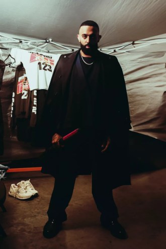Picture of a man looking at the camera, wearing black, and holding a katana.